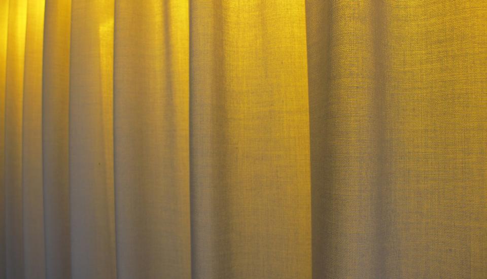 Detalje - det gule lys bag gardinet fremhæver stofligheden og skaber miljø