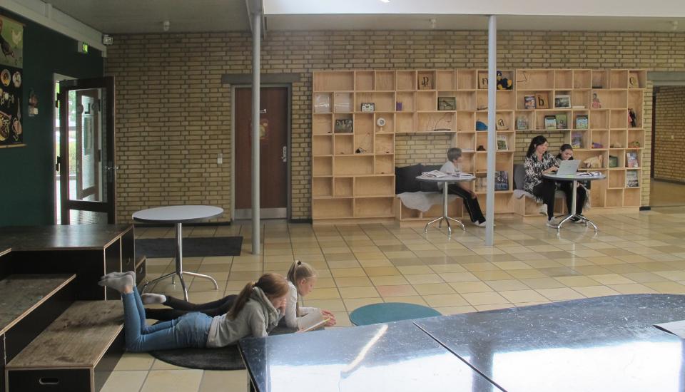 Udstillingsvæg med opholdsnicher og bløde gulvtæpper til ophold på gulvet giver mange måder for eleverne at opholde sig i rummet på